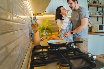 lovely couple hugging on the kitchen while cooking breakfast