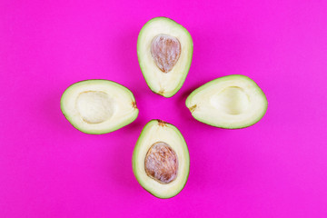 Cut avocado on a pink background. The concept of vegetarianism, healthy eating, organic food rich in vitamins. Minimalism, top view, flat lay. Copy space. Design, summer concept.