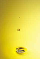 Golden yellow oil dropping and rippling over the abstract background