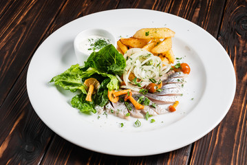 herring with baked potato on the wooden background