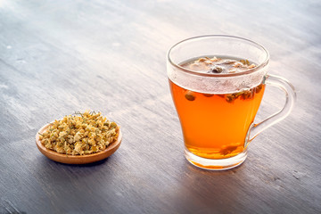 Herbal tea with pharmaceutical chamomile on a gray wooden table. Copy space