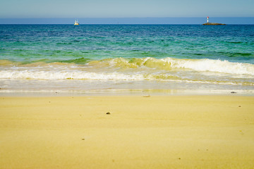 Seascape sandy beach with lighthouse on horizon