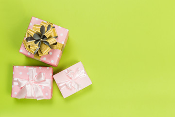 Gift box wrapped in pastel  paper with pink ribbon on green surface. Top view  with copy space.