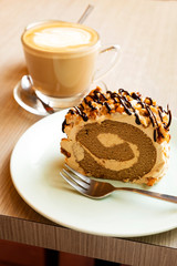 Hot latte and roll cake on a wooden table