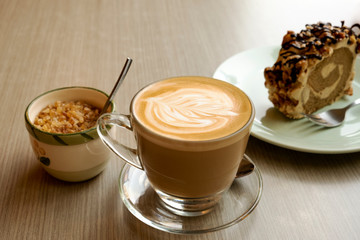 Hot latte and roll cake on a wooden table