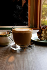 Hot latte and roll cake on a wooden table