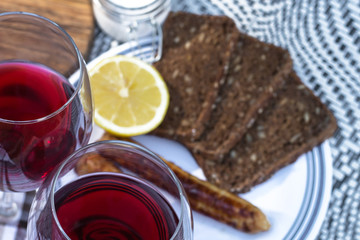 Picnic, barbecue in nature. Red wine, grilled sausages, vegetables and bread on a beautiful tablecloth.