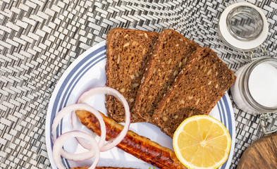 Picnic, barbecue in nature. Grilled sausages, vegetables and bread on a beautiful tablecloth.