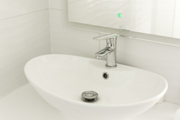 Chrome faucet, sink and washbasin. Modern white bathroom interior.