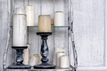 Candles with vintage stand on shelf, gray wall background, toned. Close-up, copy space