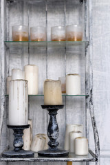 Candles with vintage stand on shelf, gray wall background, toned. Close-up, copy space