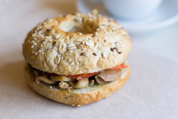 Bagel with tomatoes, eggplant, sesame on the table in cafe. Close-up, copy space