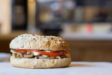 Bagel with tomatoes, eggplant, sesame on the table in cafe. Close-up, copy space