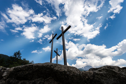 Three Christian crosses above a hill with blue sky and clouds. Religious symbol of good friday