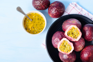 Fresh passion fruit and juice in a bowl, top view