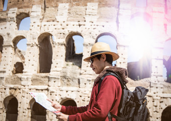 Asian  man  traveler looking at tourist map in Rome in front of Colosseum ,Italy