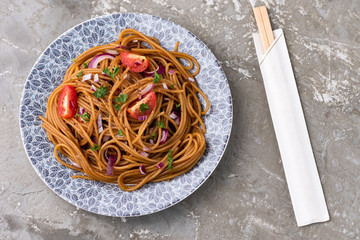 Udon stir fry noodles with vegetables in plate with chopsticks