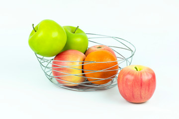 Apples and oranges in a decoratively wire basket put on isolated white background and there is an apple outside the wire basket with clipping path.