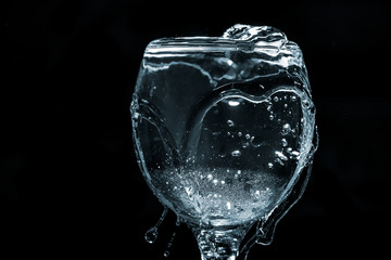 Pour water into glass on black background.