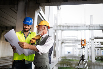 Engineer and building site manager dealing with blueprints and plans