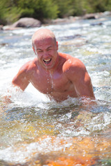 Muscle man dive in the mountain river in a bright summer day
