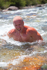 Muscle man dive in the mountain river in a bright summer day