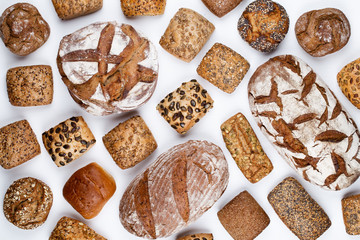 Gold rustic crusty loaves of bread and buns on wooden background. Still life captured from above top view, flat lay.