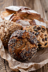 Gold rustic crusty loaves of bread and buns on wooden background. Still life captured from above top view, flat lay.