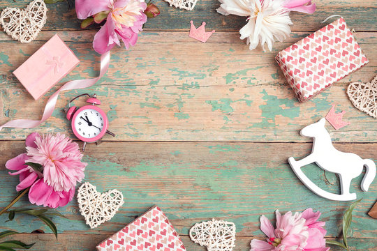 Festive frame of  pink peonies, gifts and hearts on an old turquoise background with shabby paint. Little girl birthday concept. Place for text.