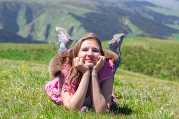 A happy woman lies on the grass propping her head in her hands