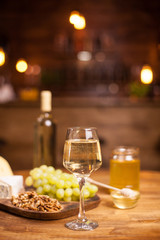 Fototapeta na wymiar Rafined still life of wine, grapes,different cheeses over rustic wooden table in a vintage pub