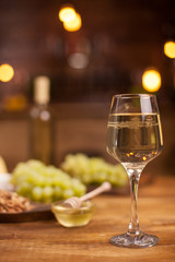 A glass of old white wine next to a bowl of delicious honey on a wooden table