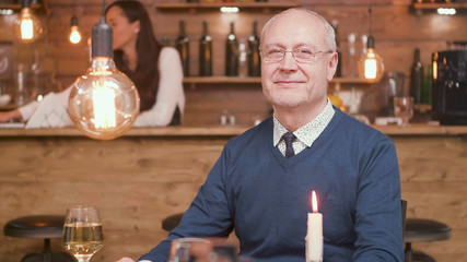 Senior man at restaurant table smiling to the camera