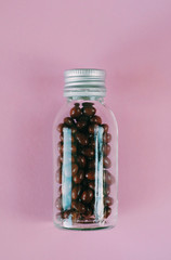 Isolated Dietary supplement pills in the glass vial on the pink background. Vitamin pills. Health care treatment