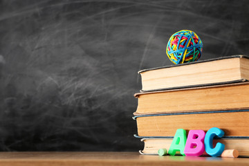 education and back to school concept. books and chalks in front of classroom blackboard