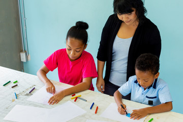 Young teacher giving African American kids an art lesson and teaching how to draw inside indoors room in natural ambient light