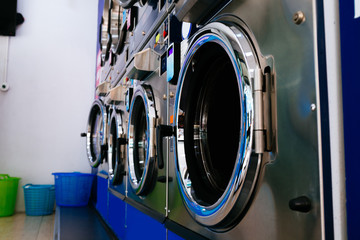 Bunch of professional industrial washing and drying machines in laundry service store - clothing cleaning business concept