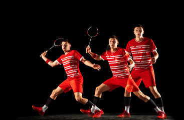 Fototapeta na wymiar Young man playing badminton isolated on black background in mixed light. Male model in sportwear and sneakers with the racket in action, motion in game. Concept of sport, movement, healthy lifestyle.