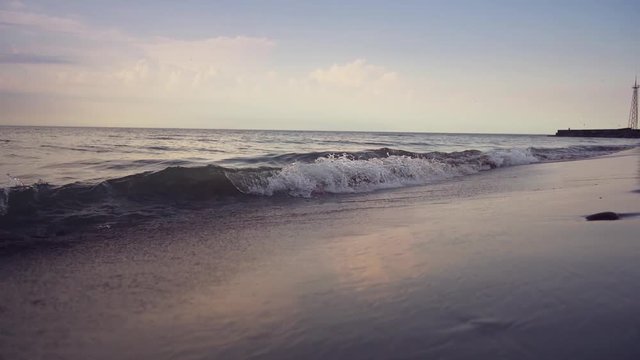 Blue ocean waves lapping over empty beach. Amazing sunset landscape. Slow motion footage. Steadicam.