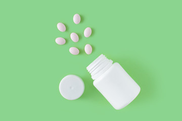 White pills and bottle on green background. Medical pharmacy concept. Probiotics benefits.