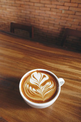 a cup of latte art coffee on wooden background