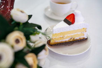 A piece of cream cake on plate, white table background, topping is strawberry on top. Colorful of delicious cake concept. Royalty high quality stock image.