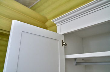 Kids wardrobe on log wall background. Classic children's furniture in white color close-up
