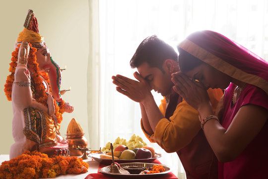 Husband and wife praying with hands joined in front of Ganesha Idol on the occasion of Ganesh Chaturthi	