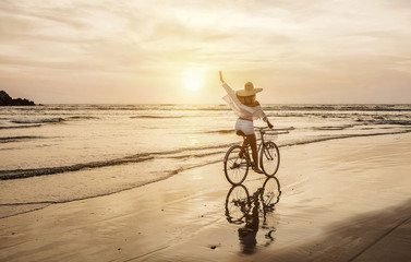 Happiness woman traveler with her bicycle rides on sea coastline