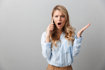 Photo of perplexed blond businesswoman with long curly hair worrying while calling on smartphone