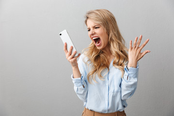 Photo of angry puzzled businesswoman with long curly hair worrying and screaming while calling on smartphone