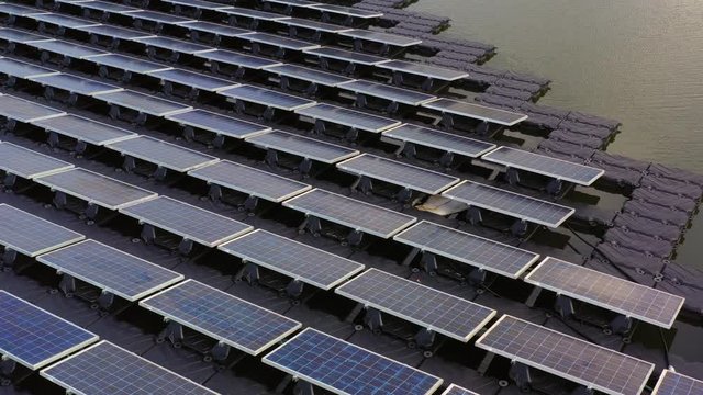 Solar panels in aerial view, rows array of polycrystalline silicon solar cells or photovoltaics in solar power plant floating on the water in lake.