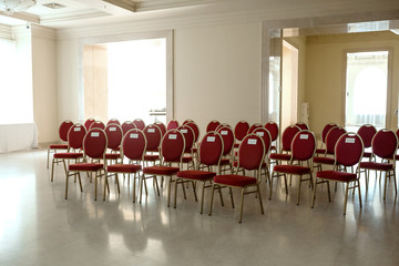 Wedding ceremony in the banquet hall indoors. Rows of chairs for guests at the wedding. A chair in red velvet with gold and a nameplate family