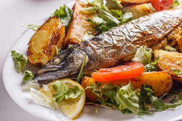 Baked stuffed fish with potatoes on the plate